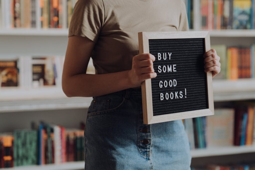 woman-in-brown-crew-neck-t-shirt-and-blue-denim-jeans-holding-black-and-white-book
